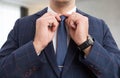 Male hands adjusting blue tie