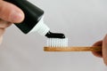 Male hands with a black toothpaste and a bamboo toothbrush