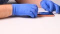 Male hands in blue gloves replaces a broken tempered glass screen protector for a smartphone. A man prepares a Royalty Free Stock Photo