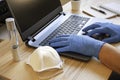 Male hands in blue protective gloves working on modern laptop. Specialist doctor in blue latex gloves. Medical mask and test tube