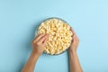 Male hands and bowl popcorn on background