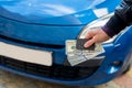 male hands in a business suit hold dollars and car keys on a background of blue cars Royalty Free Stock Photo