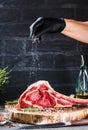 Male hands of butcher or cook holding tomahawk beef steak on dark rustic kitchen table background.
