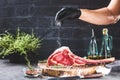 Male hands of butcher or cook holding tomahawk beef steak on dark rustic kitchen table background