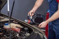 Male hands with canister in open hood of car