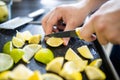 Male hands slicing lemons and limes on a black tray Royalty Free Stock Photo