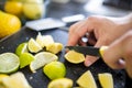 Male hands slicing lemons and limes on a black tray Royalty Free Stock Photo