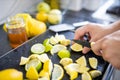 Male hands slicing lemons and limes on a black tray Royalty Free Stock Photo