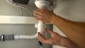 Male hands checking clogged water pipes, repairing plumbing leaks, closeup