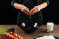 Male hands chef chefs break the egg on a wooden brown table in a black bowl. Black background. The concept of cooking food. Close- Royalty Free Stock Photo