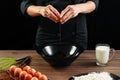 Male hands chef chefs break the egg on a wooden brown table in a black bowl. Black background. The concept of cooking food. Close- Royalty Free Stock Photo