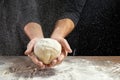 Male hands chef close-up, knead the dough, cook the dough on a dark background