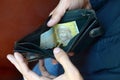 A male hands with coins with small Ukrainian bills and black old purse