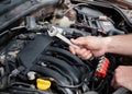 Male hands with combination spanner over the open car bonnet, close up, selective focus Royalty Free Stock Photo