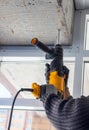 Male hands of construction worker drills hole in concrete with hand drill. the process of drilling holes in concrete beams and