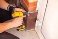 Male hands of construction worker tighten and fix screws and self-tapping screw with electric cordless screwdriver for home