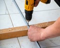 Male hands of construction worker tighten and fix screws and self-tapping screw with electric cordless screwdriver for home