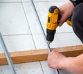 Male hands of construction worker tighten and fix screws and self-tapping screw with electric cordless screwdriver for home