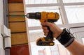 Male hands of construction worker tighten and fix screws and self-tapping screw with electric cordless screwdriver for home