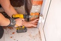 Male hands of construction worker tighten and fix screws and self-tapping screw with electric cordless screwdriver for home