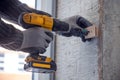 Male hands of construction worker tighten and fix screws and self-tapping screw with electric cordless screwdriver for home