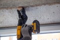 Male hands of construction worker tighten and fix screws and self-tapping screw with electric cordless screwdriver for home