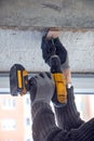 Male hands of construction worker tighten and fix screws and self-tapping screw with electric cordless screwdriver for home