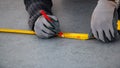 Male hands of construction worker wearing special gloves measure the details with construction tape and mark the construction