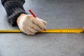 Male hands of construction worker wearing special gloves measure the details with construction tape and mark the construction