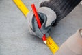 Male hands of construction worker wearing special gloves measure the details with construction tape and mark the construction