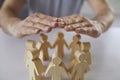 Male hands covering and protecting team of people made of wood Royalty Free Stock Photo