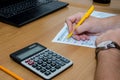 Male hands fill out tax forms 1040 on the background of a calculator and laptop. Office concept.