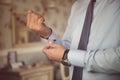 Male hands fixing stylish silver cufflinks on blue shirt cuffs sleeves in formal suit