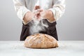 The male hands in flour and rustic organic loaf of bread