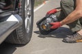 Male hands in glove and portable tire pump for inflating auto wheel. Tyre inflator air compressor with pressure gauge Royalty Free Stock Photo