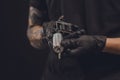 Male hands in gloves holding tattoo machine