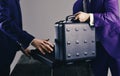 Male hands hold opened black briefcase on wooden table