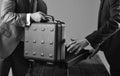 Male hands hold opened black briefcase on wooden table