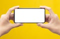 Male hands holding the black smartphone with blank screen isolated on yellow background with clipping path. Royalty Free Stock Photo