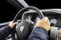 Male hands holding car steering wheel. Hands on steering wheel of a car driving. Young Man driving a car inside cabin. Multimedia