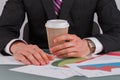 Male hands holding coffee cup with business papers on the table. Royalty Free Stock Photo