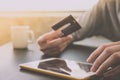 Male hands holding credit card and using Tablet with a cup of coffee on the table.Online shopping concept. Royalty Free Stock Photo