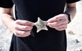 Male hands holding dead starfish washed ashore in the Japanese sea after a storm.