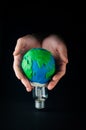 Male hands holding an electric lamp decorated as plasticine Earth planet model