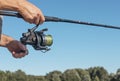 Male hands holding fishing rod or angler over blue clear sky in summer Royalty Free Stock Photo