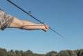 Male hands holding fishing rod and assembling it over blue clear sky in summer time Royalty Free Stock Photo