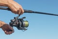 Male hands holding fishing rod closeup over blue clear sky in summer Royalty Free Stock Photo