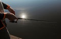 Male hands holding fishing rod closeup over river or lake with reflection of sun rays Royalty Free Stock Photo