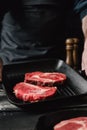 Male hands holding grill pan beef steaks kitchen Man cooking Royalty Free Stock Photo