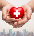Male hands holding red heart with white cross Royalty Free Stock Photo